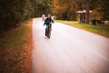 Child Riding Bicycle Along Park Path in Autumn Afternoon with Fallen Leaves