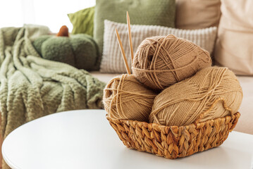 Obraz premium Basket with Yarn Balls on White Table in Cozy Living Room