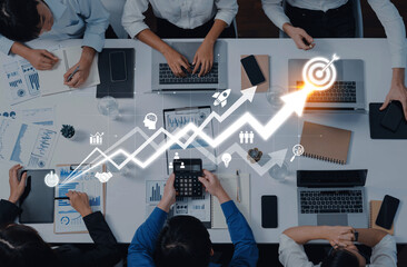 A collaborative group of professionals engaged in financial analysis with laptops and documents, showcasing teamwork and strategic planning in a modern office. Trope