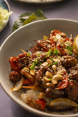 A bowl of colorful stirfried vegetables and tender meat, topped with nuts and seeds for extra texture and flavor