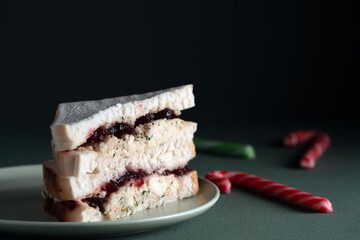 Delicious, thick-cut holiday sandwich with savory stuffing and bright cranberry sauce filling, presented with blurred festive candy cane props