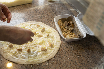Chef hands preparing pizza, showing dough, sauce, and ingredients in process without visible face, reflecting culinary craftsmanship and traditional Italian cooking.