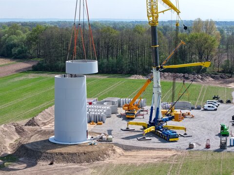 Gro&szlig;er Schwerlastkran setzt Teile f&uuml;r den Turm einer Windkraftanlage &uuml;bereinander, Luftbild, Hochbau, Windenergie, Windrad, Aufbau, Kran, Energiewende, Nachhaltigkeit, Energie, regenerativ