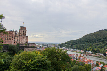 panoramic shot showing the tower of the medieval heidelberg castle to the left and the river, bridge and city with its green mountains to thee right on a misty fallday