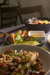 A beautifully arranged table, adorned with a variety of delicious dishes including salad, spring rolls, and stirfry
