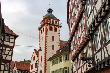 red-white stone church tower in an old german town surrounded by old medieval half-timbered (fachwerkhäuser) buildings 