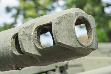 Close-up image of an artillery gun barrel, focusing on the muzzle brake with fluting pattern The...