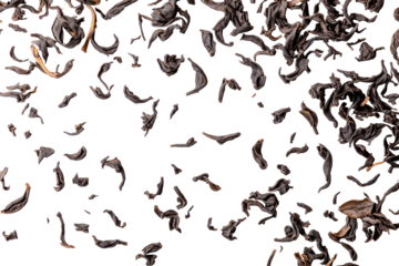 Dry, loose, black tea leaves scattered against a dark, solid background