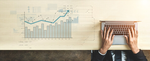 Business professional engages in data analysis on a laptop at a modern desk, examining financial charts and graphs for strategic insights and decision-making. Scalp