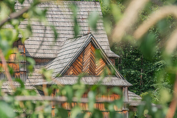 Old wooden Orthodox church in an ancient Central European village, set amidst autumn or late spring foliage Rustic structure with multiple levels and pointed roofs in a soft, diffuse light No peopl