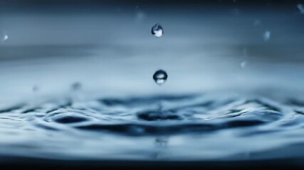 Falling water droplets impacting calm liquid surface, ripple effect