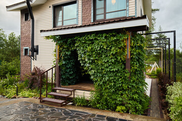 The houses charming entrance features vibrant greenery and contemporary design, inviting guests