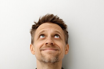 A man looks up with a thoughtful and hopeful expression on his face, contemplating something unseen above.