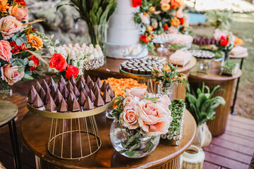 Gourmet chocolate sweets and floral arrangements on a wedding dessert table