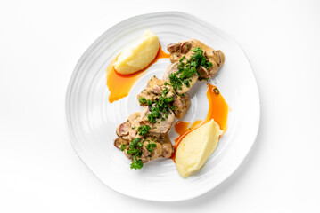 Gourmet plated dish with stuffed poultry slices, mashed potato quenelles, orange sauce drizzle, and herb garnish. Fine dining presentation on white plate, top view.