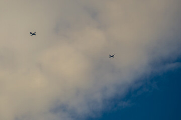 Two military aircraft flying under cumulus in blue sky