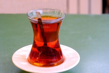 Close-up of traditional Turkish tea in a slim-waisted glass. Enjoyable tea on a white plate....