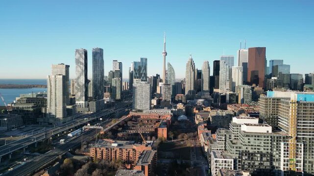 Wide 4K drone shot of downtown Toronto skyline under bright blue sky &mdash; CN Tower standing tall among modern buildings. Perfect for travel videos, real estate promos, and city branding