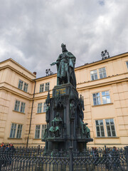 Fototapeta premium A monumental bronze statue of a historical monarch standing on an ornate stone pedestal decorated with allegorical figures in front of a classical building.