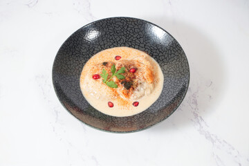 Dahi Baray or bhalla Yogurt Lentil Fritters Garnished with Pomegranate and Spices in bowl isolated on marble background closeup side view