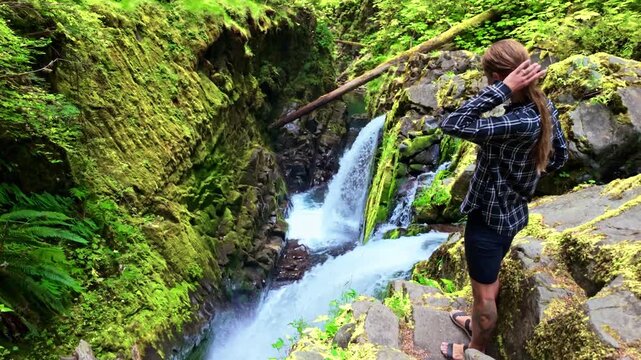 A girl is captured enjoying the beautiful scenic view of the powerful Sol Duc Falls cascading on a bright summer day in Olympic National Park