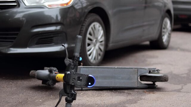 Yellow electric scooter lies on the ground after crash. Accident with car and electric scooter.