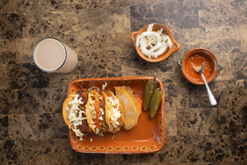 Mexican street food meal with tacos, horchata, salsa, and onions on a stone table