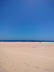 Golden sand dunes of Fuerteventura in warm sunlight. Desert landscape with soft sand lines and a clear blue sky. The natural beauty of the Canary Islands, perfect for travel or nature themes.
