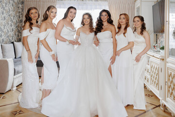 Naklejka premium Bridal party celebrating together in stylish white outfits in a cozy room