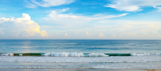 Tranquil Seascape With Gentle Waves Rolling Onto Sandy Beach Under Clear Blue Sky Horizontal