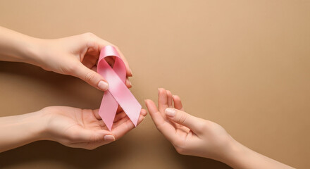 Hands offering a pink ribbon for breast cancer awareness and support
