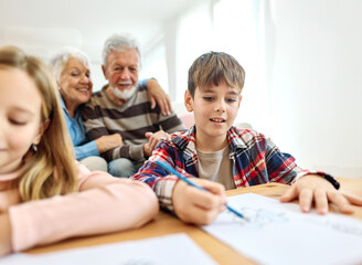 Portrait of grandparents and grandchildren having fun together reading and writing homework at home