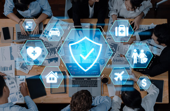 A diverse team collaborates around a table, analyzing reports and discussing insurance strategies while surrounded by digital icons symbolizing various coverage sectors. Trope