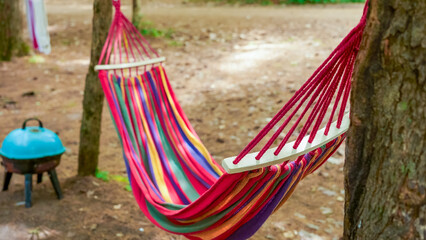 Colorful hammock is suspended between two trees in a serene outdoor setting, inviting relaxation and leisure in a natural environment