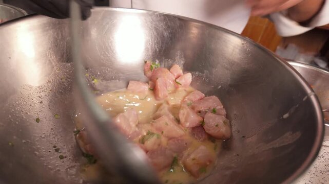 Chef mixing fresh peruvian ceviche in restaurant kitchen