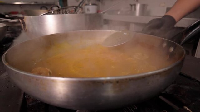 Professional chef stirring seafood stew in restaurant kitchen