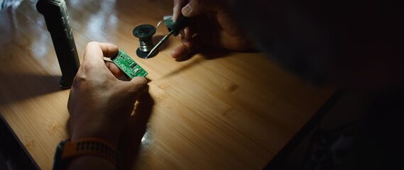 Technician soldering electronic circuit board under bright work lamp illumination - Powered by Adobe
