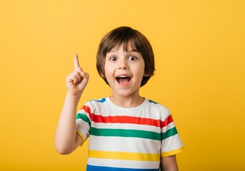 Excited Child in Striped T-Shirt Pointing Up — Expressive Portrait on Solid Yellow Background with Joyful Gesture