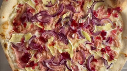 A closeup image showcases a tantalizing pizza topped with flavorful onion, savory meat, and fresh fruit