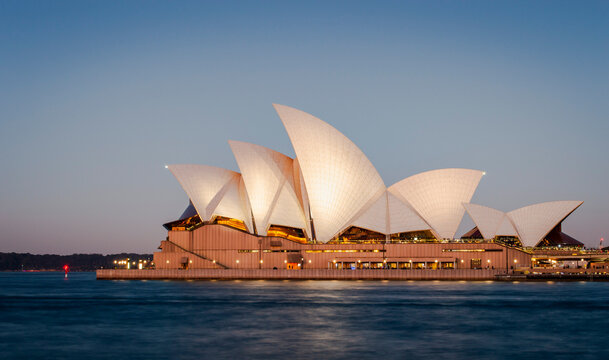 Sydney, Australia, July 26, 2023. Beautiful waterfront view of Sydney Opera House lights up in the evening.