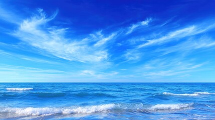 Obraz premium Tranquil Ocean View Under Bright Blue Sky with Wispy Clouds and Gentle Waves Lapping at the Shoreline Along a Serene Coastal Landscape