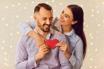 Portrait of a happy couple holds a red heart, capturing the love and joy. The image radiates...