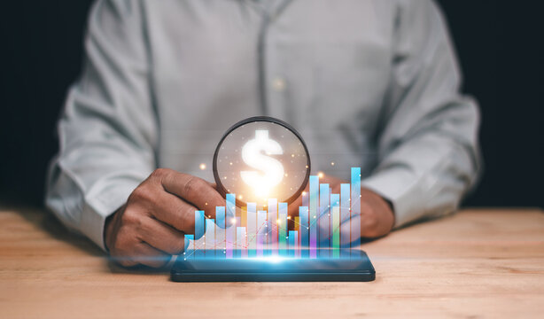 Financial analysis and investment concept. Man holding magnifying glass with glowing dollar sign and growth chart on smartphone. Profit management, data analytics and economic success strategy.
