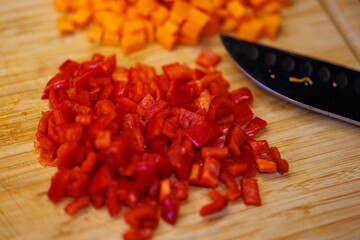 Freshly chopped red bell peppers and carrots on a wooden cutting board ready to cook