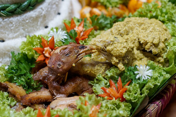 Traditional Indonesian chicken dish “ayam ingkung” with yellow coconut sauce and tumpeng rice