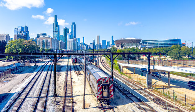 Chicago, Illinois, USA. Oct 11, 2025. A panoramic view captures a train on multiple tracks with Chicago's iconic skyline and Soldier Field stadium under a clear blue sky.