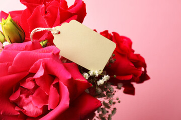 Blank tag and beautiful flowers on pink background, closeup