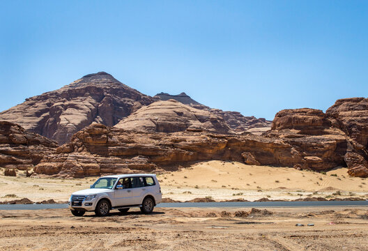Alula, Saudi Arabia, April 3, 2024. View of a white car at Alula desert with rock mountains at background in a sunny day.