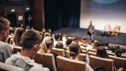 Speaker giving a talk in conference hall at business event. Rear view of unrecognizable people in...
