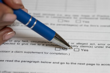 Feminie fingers holding a pen on the legal questionaire form to determine a yes or no answer
